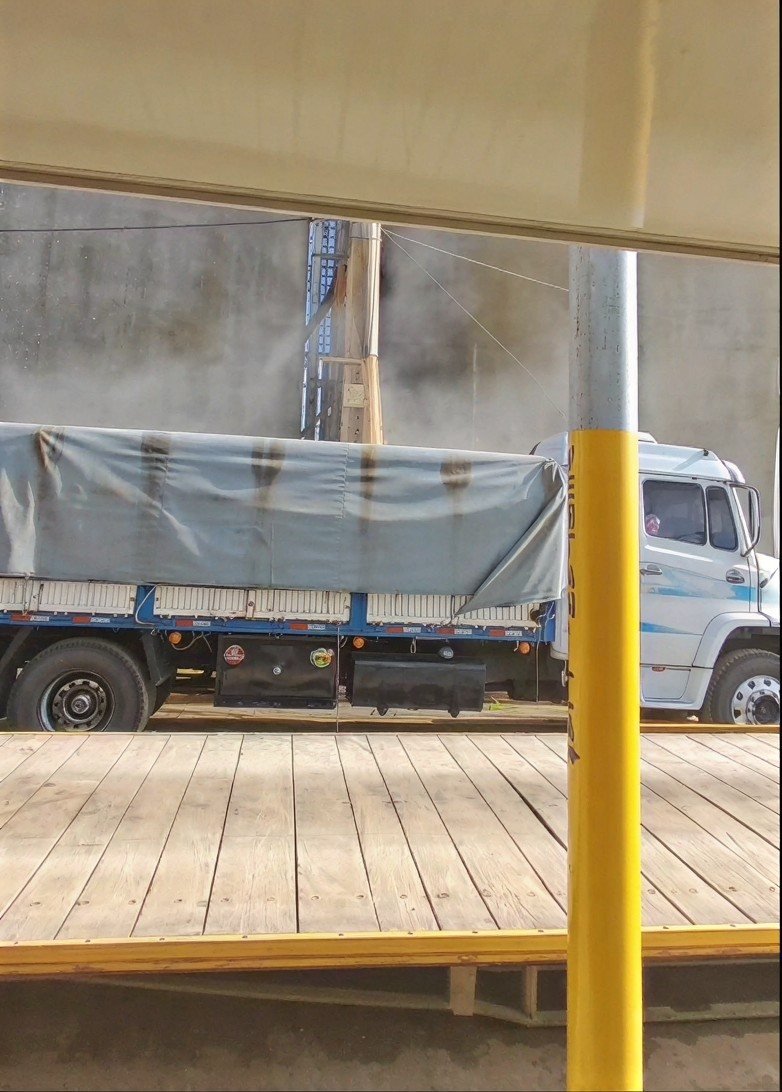 A covered road truck under the loadout with a dust cloud above the truck body